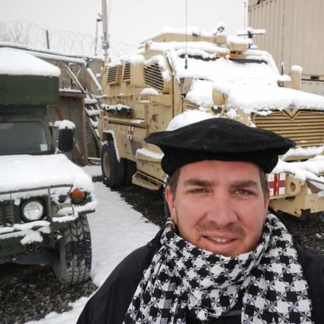 Man in heavy snow on military base with tanks